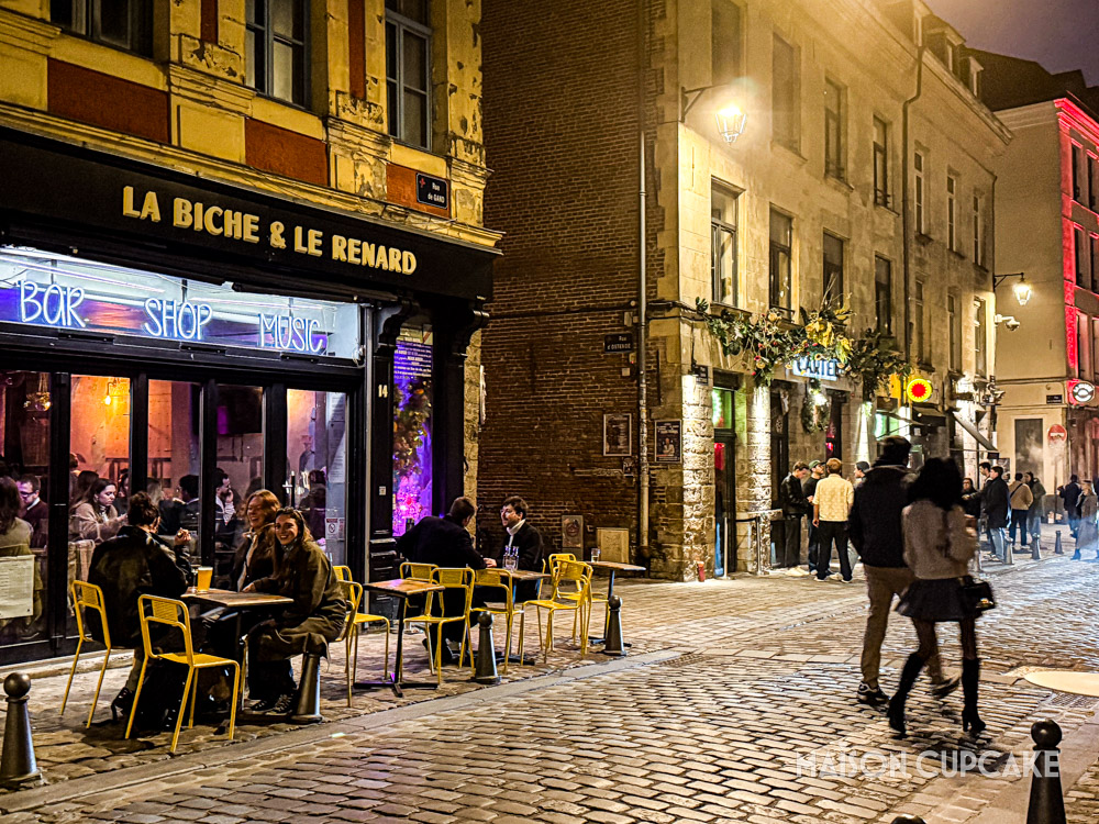 Night time bar scene with drinkers at outdoor tables in central Lille.