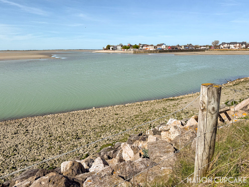 Le Crotoy as seen across bay from the locks at Bassin de Chasse with rocks and fence in foreground